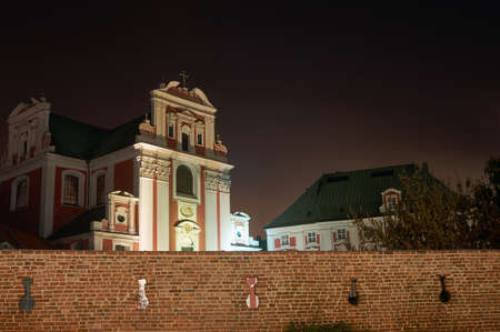 Baroque church by medieval wall at night in Poznanの写真素材