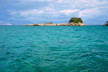 Rocky island in the Ionian sea and the mountains in Albaniaの写真素材