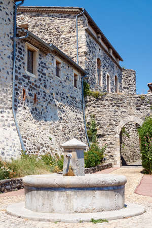 A stone well and medieval buildings in Saint-Vincent-de-Barres in Franceの写真素材