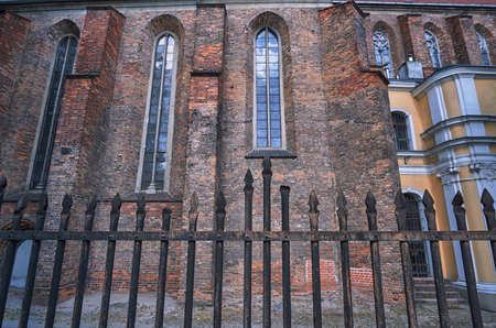 Metal fence and a wall of a Gothic church in Poznanの写真素材