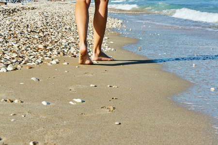 Bare feet of a woman on a sandy beach on the Greek island of Corfuの写真素材