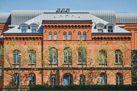 trees in front of a red brick building in Poznan