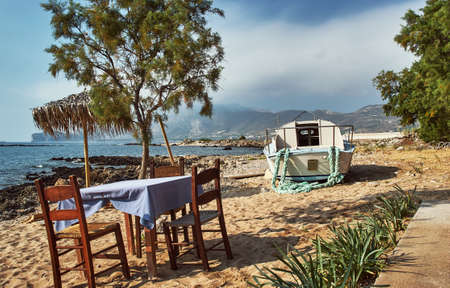 Greek tavern table and motorboat on the island of Creteの写真素材
