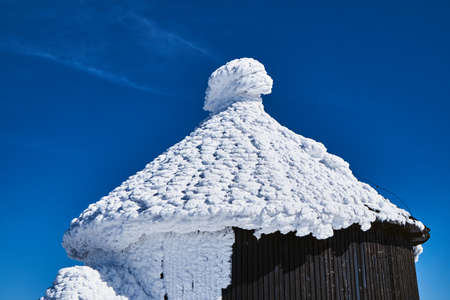 Snow cap on a roof of a wooden chapel in the Giant Mountains in Polandの写真素材