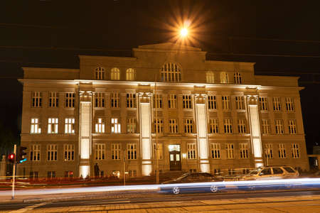The facade of a monumental and historic building illuminated at night in Poznanの写真素材