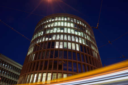 Elevation of a modernist, round building and traffic light at night in Poznan