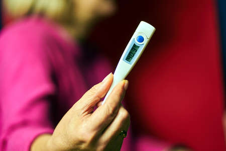 Electronic thermometer showing high fever in a womans handの写真素材