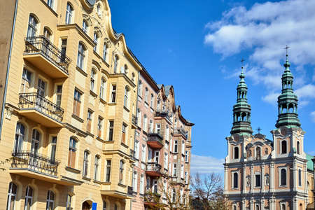 facade of a historic tenement house and belfries of the baroque church in Poznanの写真素材
