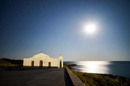 The facade of the Orthodox chapel illuminated by moonlight on the coast of the island of Zakynthos in Greeceの写真素材