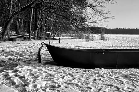 Rowing boat in the snow on a frozen lake in Poland, monochromeの写真素材