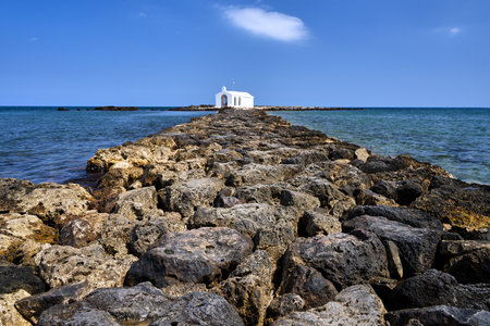 A white Orthodox chapel on a stone headland in the town of Georgioupoli on the island of Crete in Greeceの写真素材