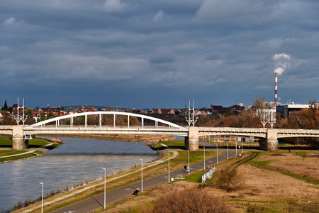 Steel structure of the bridge over the Warta River and smoke from an industrial chimney in Poznan,...