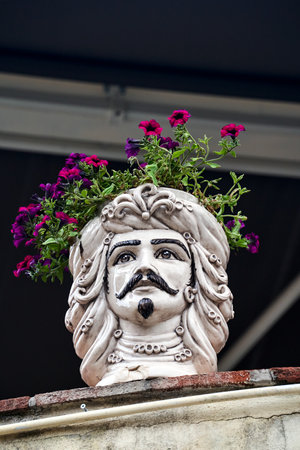 Flowers in a decorative traditional porcelain pot in the shape of a human head in a house on the island of Sicily, Italyの写真素材
