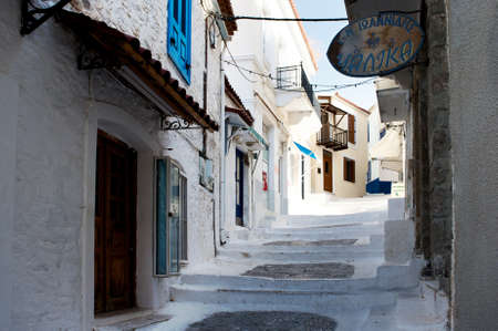 Street with white road and old houses in the village at the Poros island, Greeceの写真素材