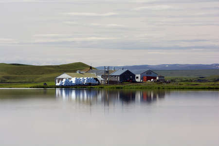 Small farm reflecting in still water on a cloudy summer day, Myvatn lake, Icelandのeditorial素材