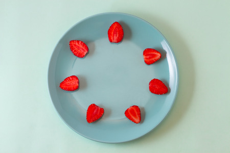 Bright juicy strawberries on a pastel pink dish spread out around the edges of the plate.の写真素材