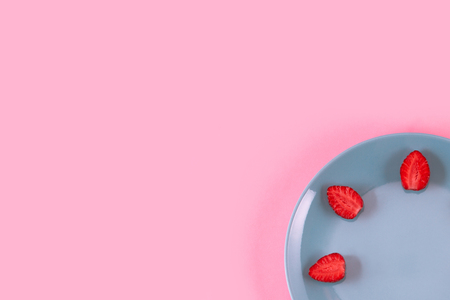 Bright juicy strawberries on a pastel pink dish spread out around the edges of the plate.の写真素材