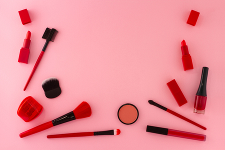 Group of items for make-up in red shades layout on a pink background.の写真素材