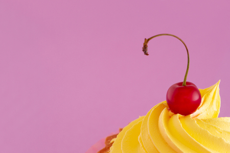 A bright ripe cherry berry on the top of a delicious cake on a pastel purple background. Macrophotography.の写真素材
