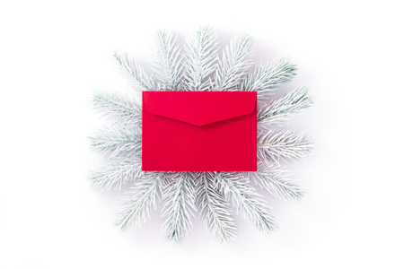 Conceptual photo. White hand painted spruce branches frame a bright red envelope symbolizing the message.の写真素材