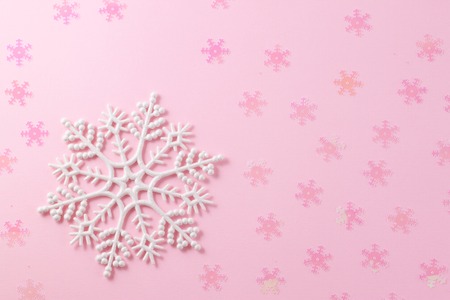 A gentle magic white snowflake from a fairy tale on a light pink background. Flat Lay layout of New Year's decorations and confetti sequins.の写真素材