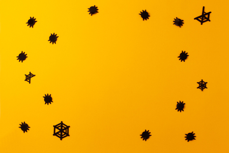 Conceptual halloween layout on a yellow-orange background. Hand made confetti in the form of spiders and webs.の写真素材