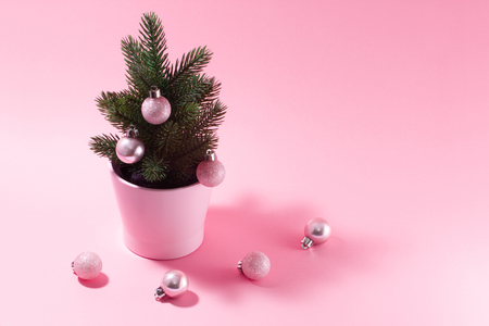 Pale pink composition on a New Year's theme. A small decorative Christmas tree with balls for decoration on a pink background.の写真素材