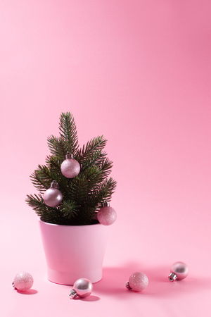 Pale pink composition on a New Year's theme. A small decorative Christmas tree with balls for decoration on a pink background.の写真素材