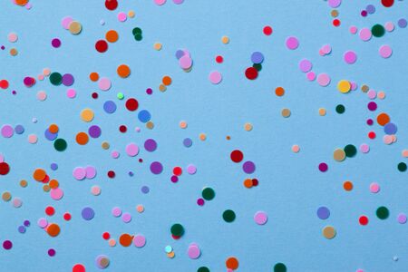 Multicolored round sequins on a pastel blue background with confetti.の写真素材