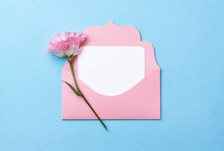 Pink envelope with white sticker inside on a pink paper background decorated with spring flowers.の写真素材