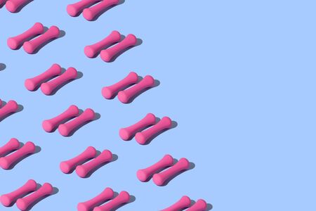 Conceptual sport pattern with pink dumbbell on a blue background with place for inscription.