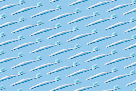 White toothbrush with blue bristles on a blue paper background.の写真素材
