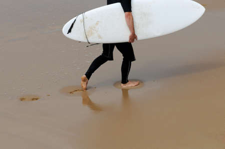 A surfer is walking on the beach の写真素材