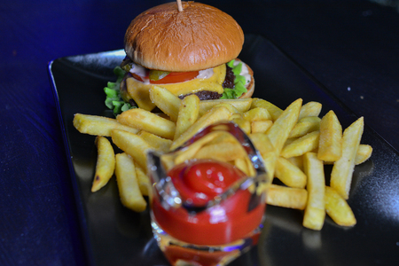 Tasty burger, french fries with sauce on black boardの写真素材