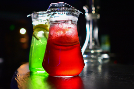 Two glass decanters, carafes, flagons with orange and berry lemonde on a wooden table with a black backgroundの写真素材