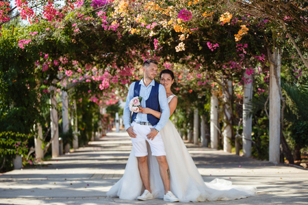 Beautiful smiling young bride and groom walking on the beach, kissing and having fun, wedding ceremony near the rocks and sea. Wedding ceremony on coast of Cyprusの写真素材