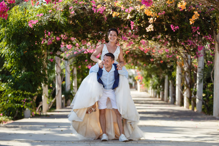 Beautiful smiling young bride and groom walking on the beach, kissing and having fun, wedding ceremony near the rocks and sea. Wedding ceremony on coast of Cyprusの写真素材