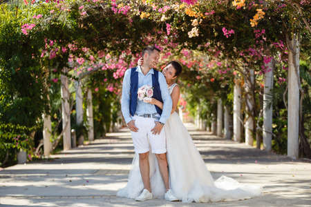 Beautiful smiling young bride and groom walking on the beach, kissing and having fun, wedding ceremony near the rocks and sea. Wedding ceremony on coast of Cyprusの写真素材