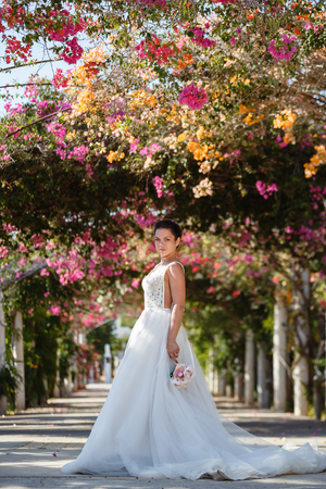 Beautiful smiling young bride and groom walking on the beach, kissing and having fun, wedding ceremony near the rocks and sea. Wedding ceremony on coast of Cyprusの写真素材
