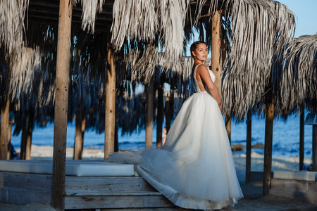 Beautiful smiling young bride and groom walking on the beach, kissing and having fun, wedding ceremony near the rocks and sea. Wedding ceremony on coast of Cyprusの写真素材