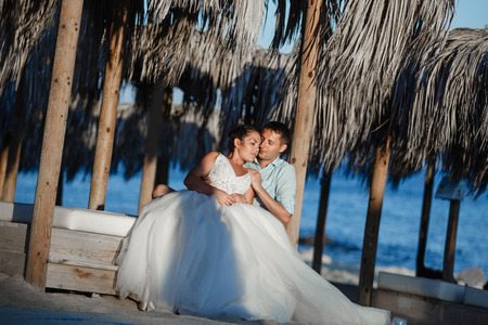 Beautiful smiling young bride and groom walking on the beach, kissing and having fun, wedding ceremony near the rocks and sea. Wedding ceremony on coast of Cyprusの写真素材