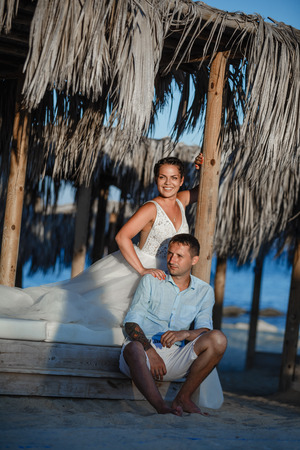 Beautiful smiling young bride and groom walking on the beach, kissing and having fun, wedding ceremony near the rocks and sea. Wedding ceremony on coast of Cyprusの写真素材