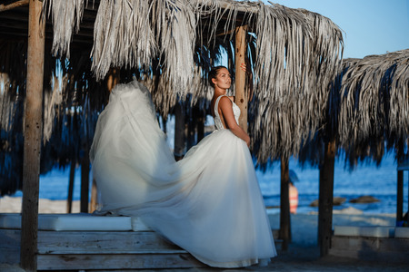 Beautiful smiling young bride and groom walking on the beach, kissing and having fun, wedding ceremony near the rocks and sea. Wedding ceremony on coast of Cyprusの写真素材