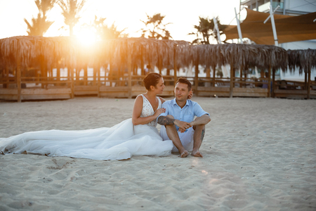 Beautiful smiling young bride and groom walking on the beach, kissing and having fun, wedding ceremony near the rocks and sea. Wedding ceremony on coast of Cyprusの写真素材