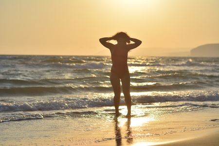 Beautiful happy brunette girl posing on the beach in a red bathing suit.の写真素材