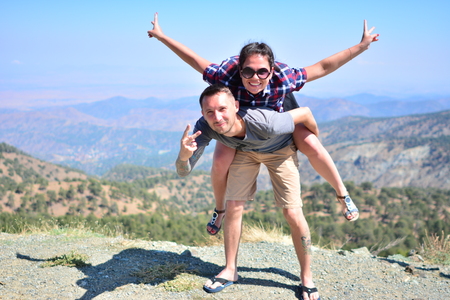 Active couple rests on a mountain peak looking on a mountain landscapeの写真素材