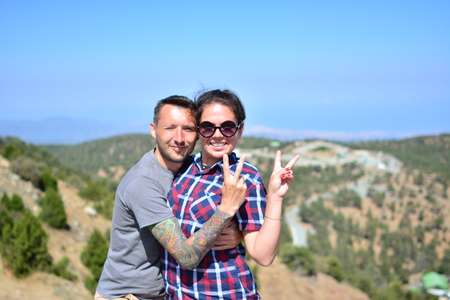 Active couple rests on a mountain peak looking on a mountain landscapeの写真素材