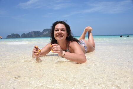 Beautiful brunette relaxes on the azure shore of the island in Thailandの写真素材
