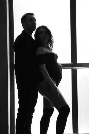 Beautiful happy couple is expecting a baby. A married couple expecting a child in a photo studio.の写真素材