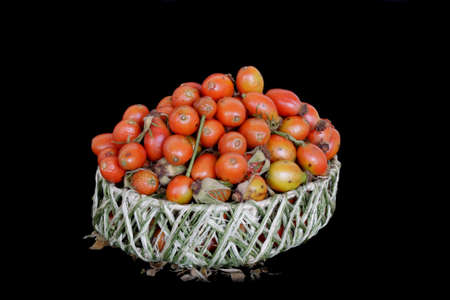 Red beries of dog-rose in wicker basketの写真素材